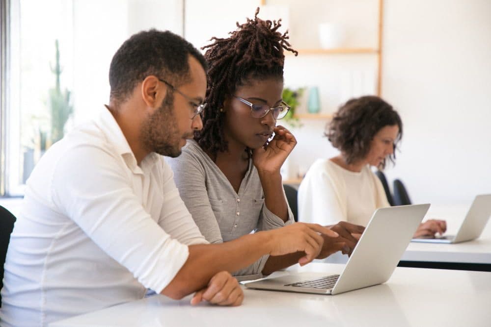 Young professionals gathered around a laptop during a collaborative work session