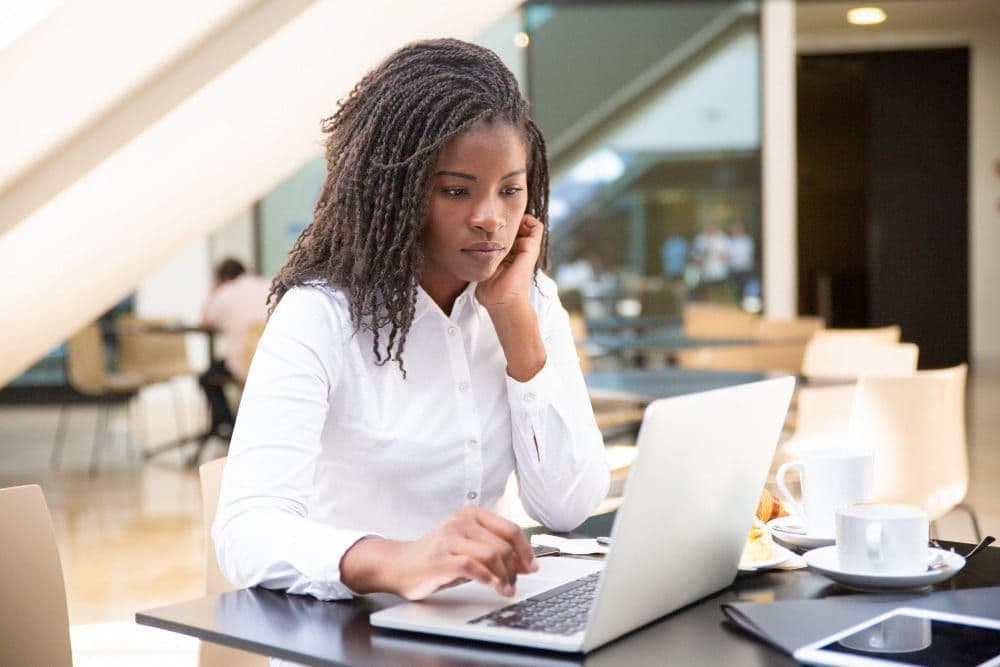 African woman working on a laptop in a bright modern workspace